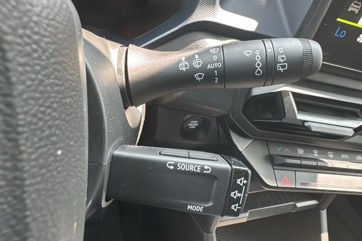 Détail du commodo gauche avec commandes audio et essuie-glace sur le tableau de bord du Dacia Duster 2025.