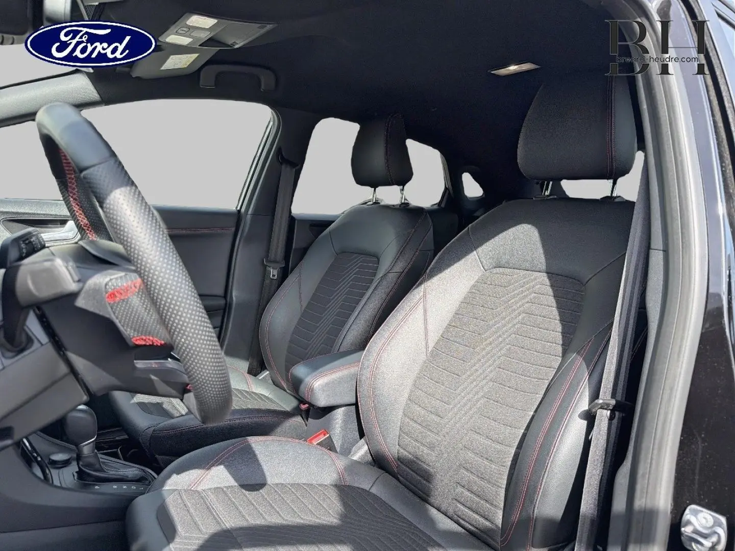 Vue intérieure côté conducteur du Ford Puma 2023 noir Agate, sièges tissu et cuir avec surpiqûres rouges et volant sport.