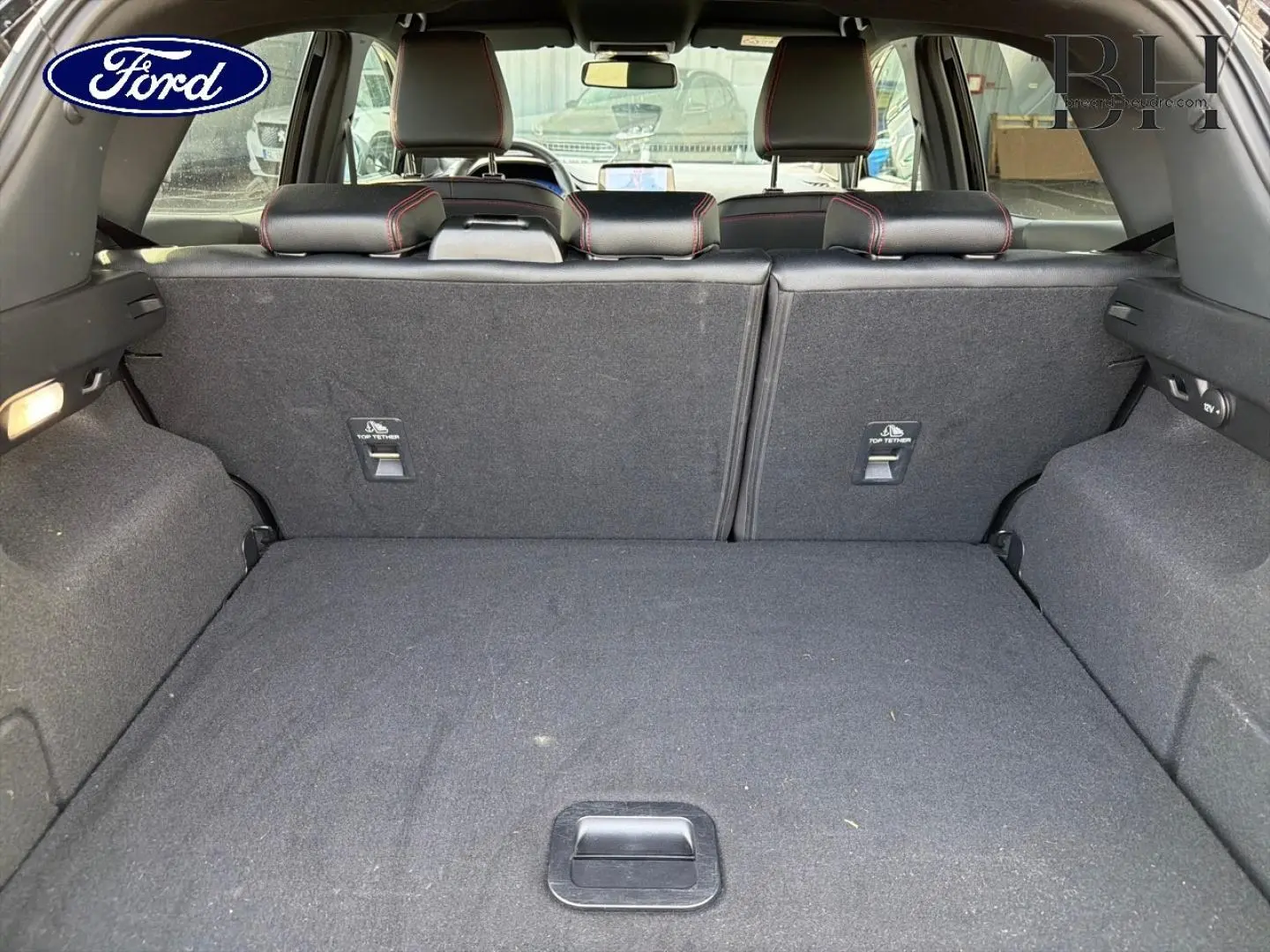 Vue du coffre arrière du Ford Puma 2023 noir Agate Métallisée, montrant les dossiers de sièges rabattus et l'espace de chargement.