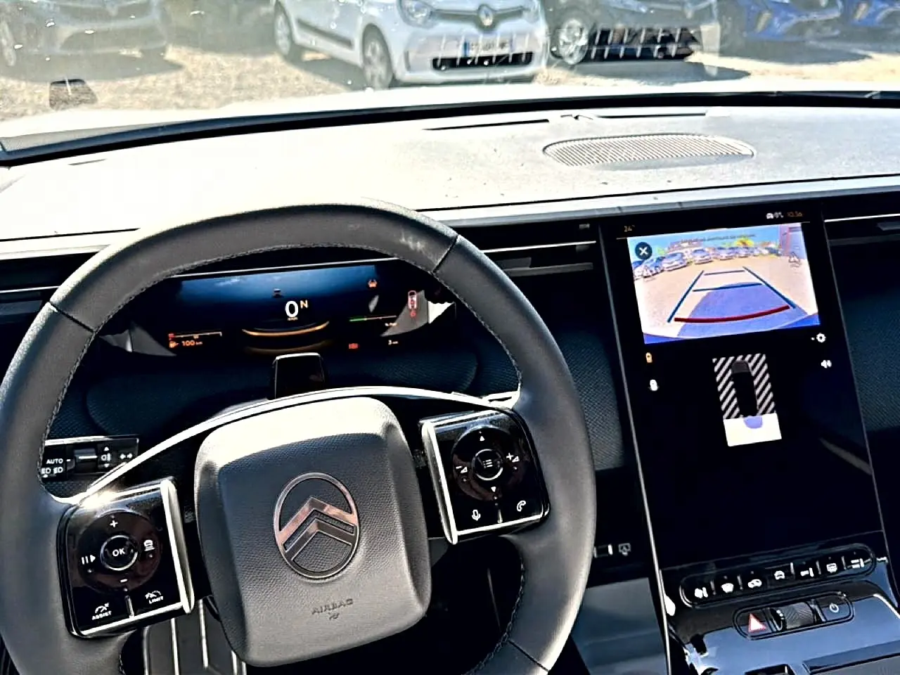 Vue intérieure centrée sur le volant noir et l'écran tactile affichant la caméra de recul du Citroën C5 Aircross blanc.