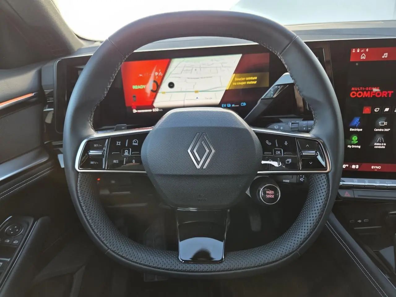 Vue intérieure centrée sur le volant noir perforé de la Renault Austral 2025 avec tableau de bord numérique et écran tactile.