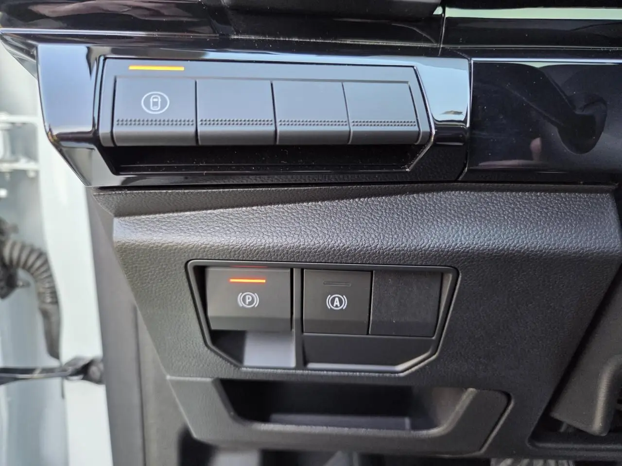 Gros plan sur les commandes de frein de parking et arrêt auto du Renault Austral E-Tech blanc nacré, côté gauche conducteur.