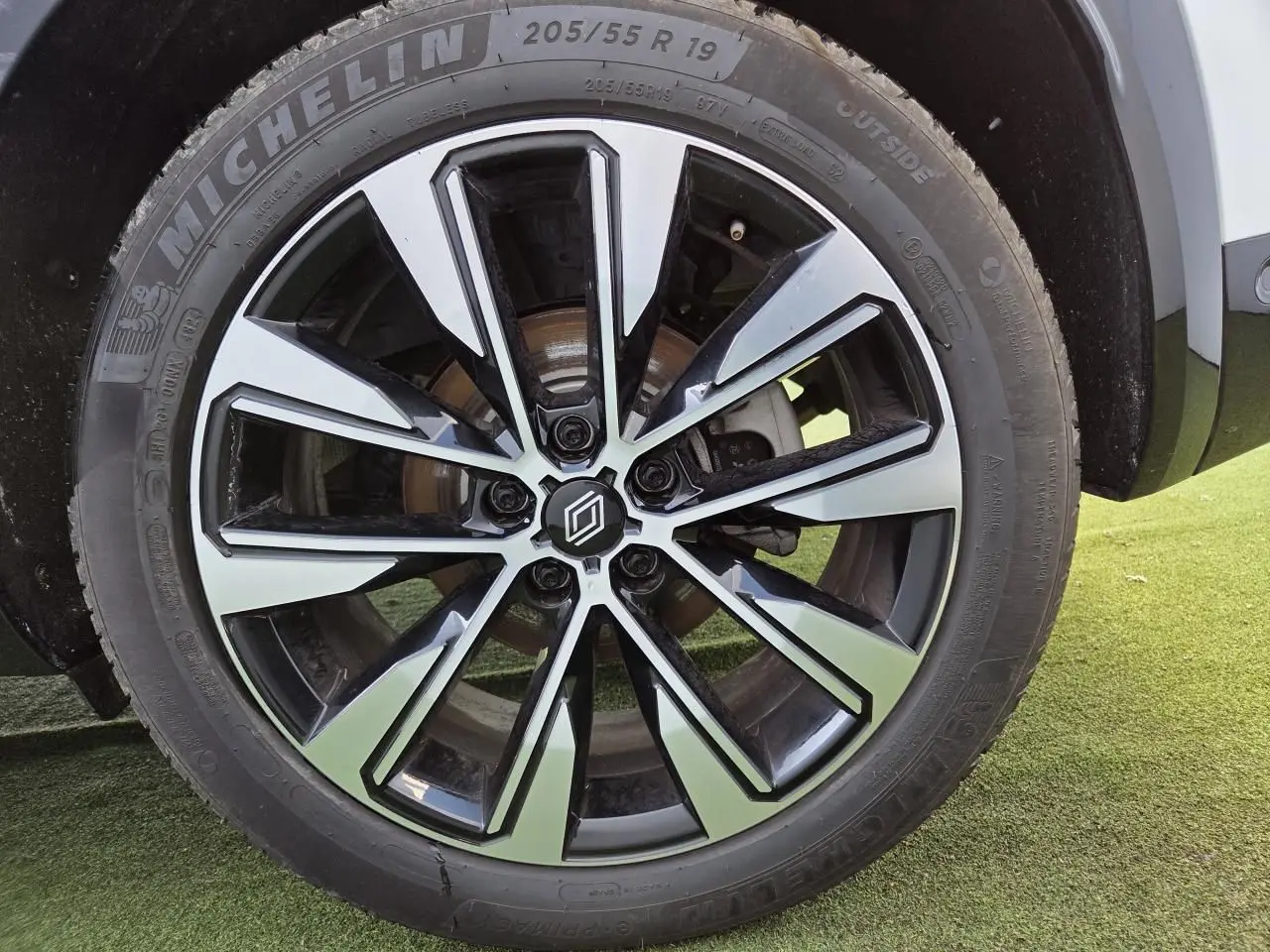 Gros plan sur la jante alliage 19 pouces diamantée noire du Renault Austral blanc nacré, roue avant côté droit.