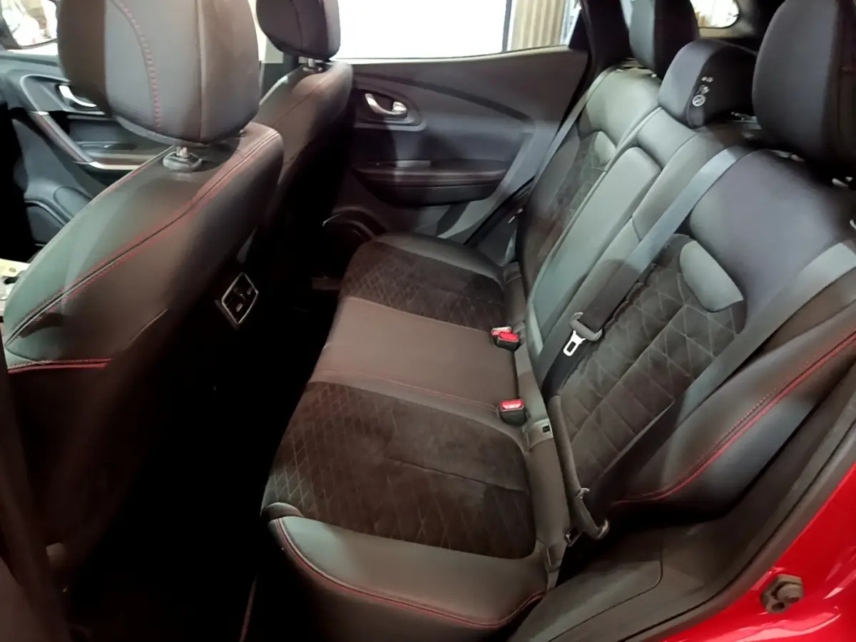 Vue intérieure arrière droite du Renault Kadjar rouge, sièges en cuir noir avec surpiqûres rouges et ceinture de sécurité visible.