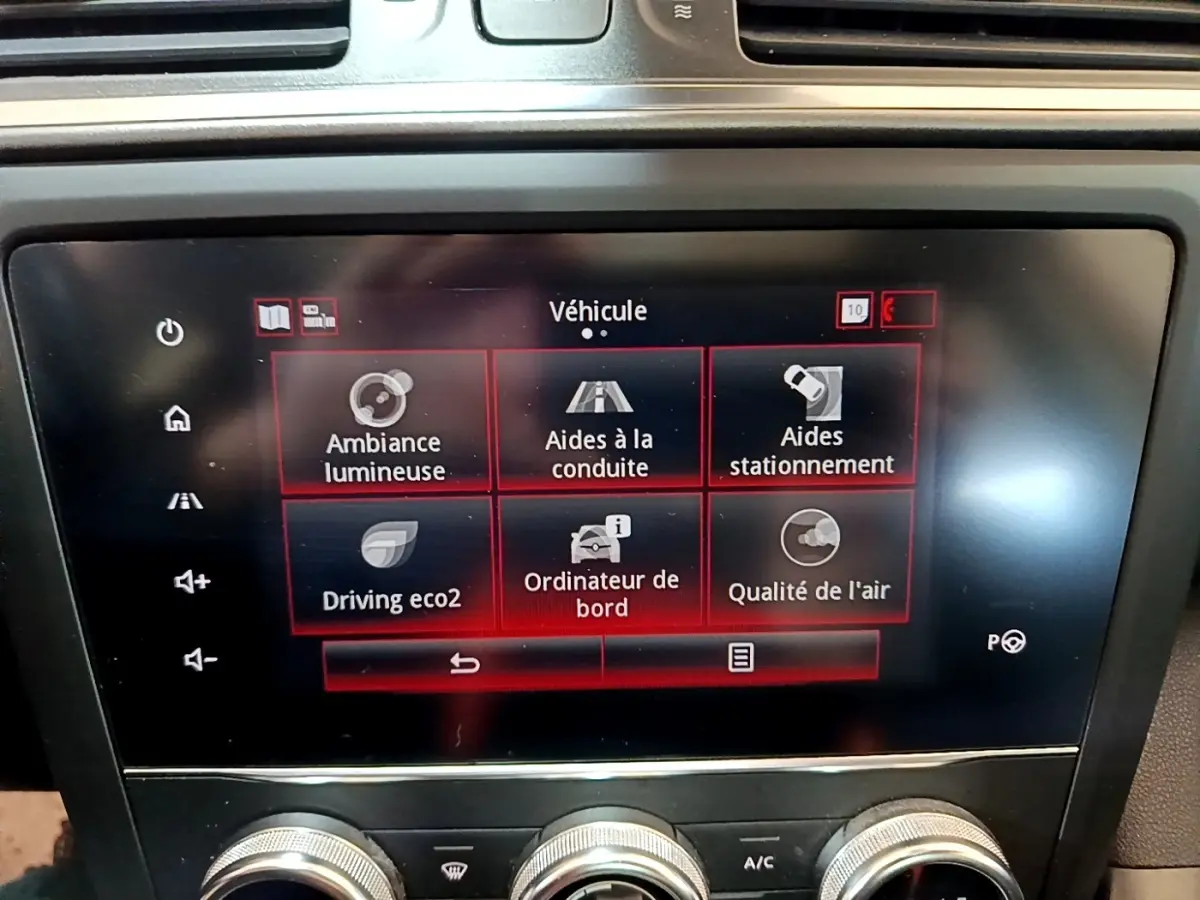 Écran tactile central du tableau de bord du Renault Kadjar rouge, affichant les options d’aides à la conduite et stationnement.