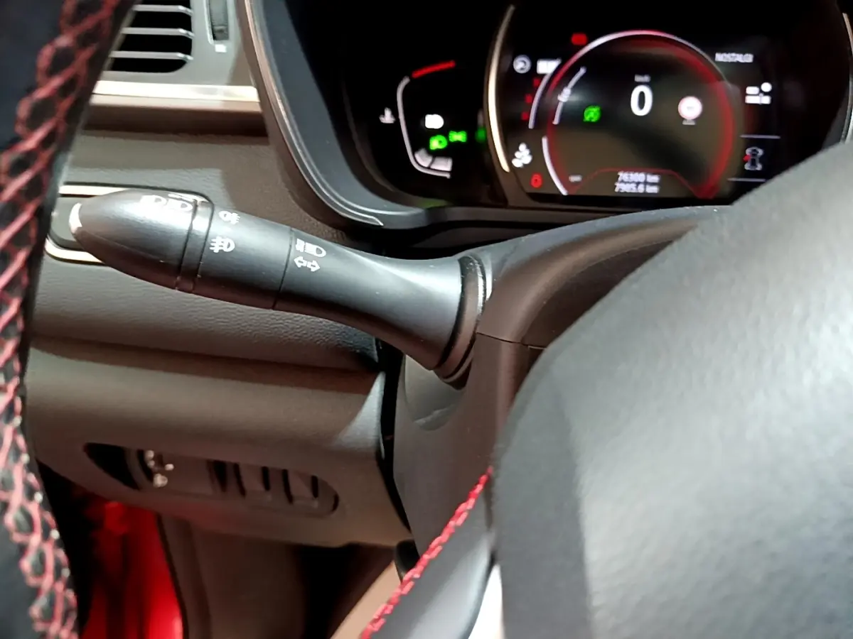 Gros plan intérieur sur le volant noir avec surpiqûres rouges et le combiné d'instruments numérique du Renault Kadjar rouge.