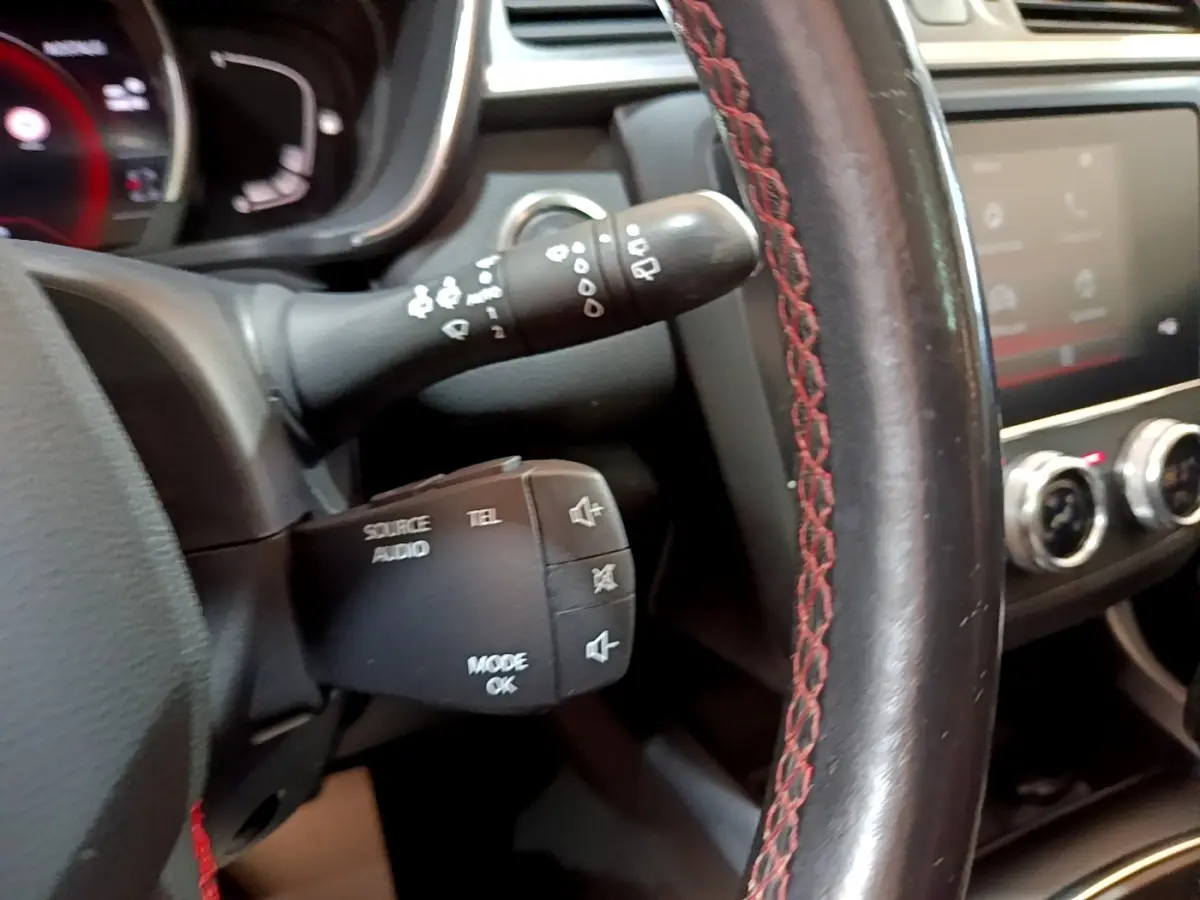 Gros plan sur le volant cuir noir avec surpiqûres rouges et commandes audio du Renault Kadjar rouge, version 2019.