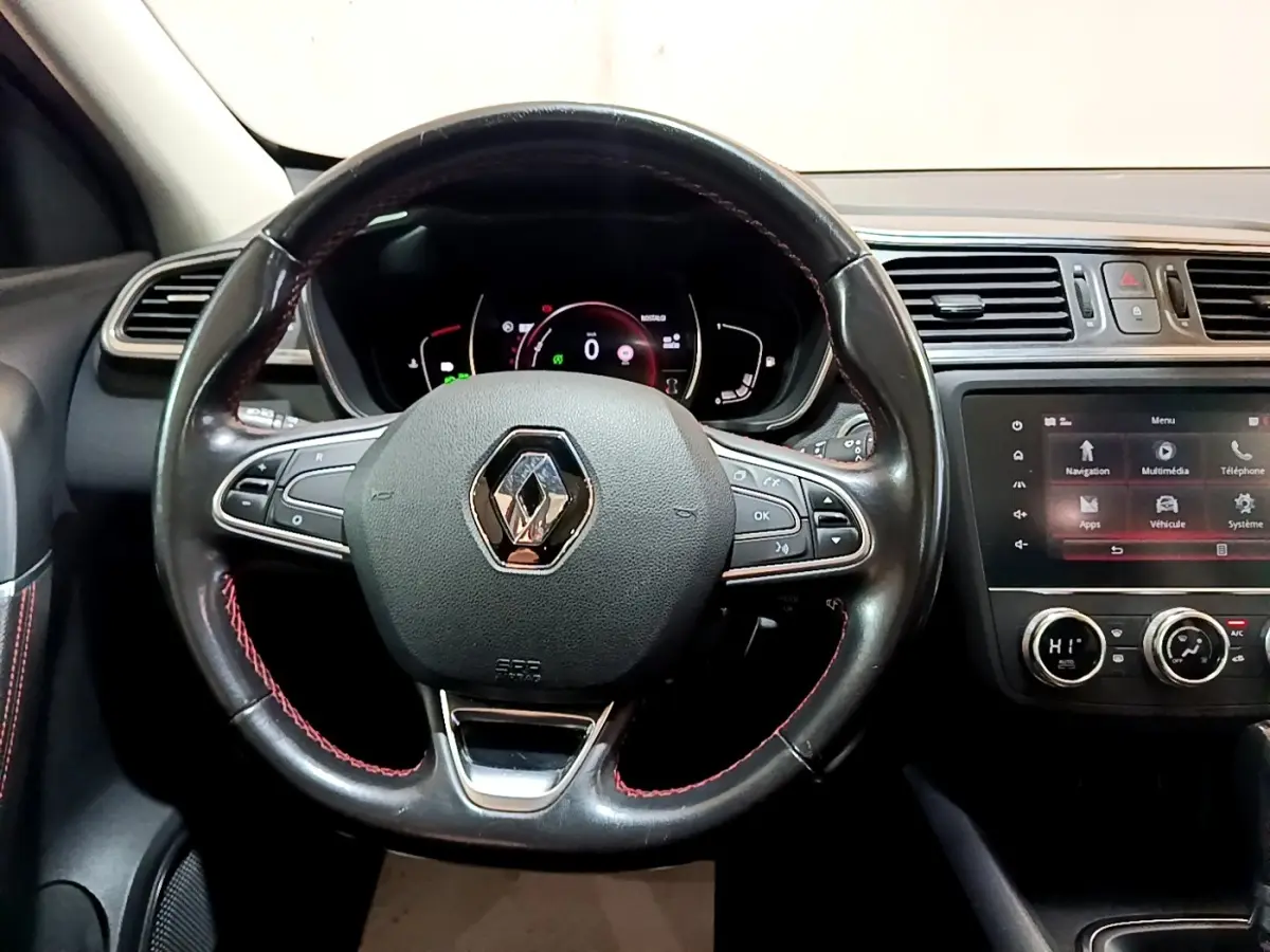 Vue intérieure centrée sur le volant cuir noir avec surpiqûres rouges et tableau de bord numérique du Renault Kadjar 2019.