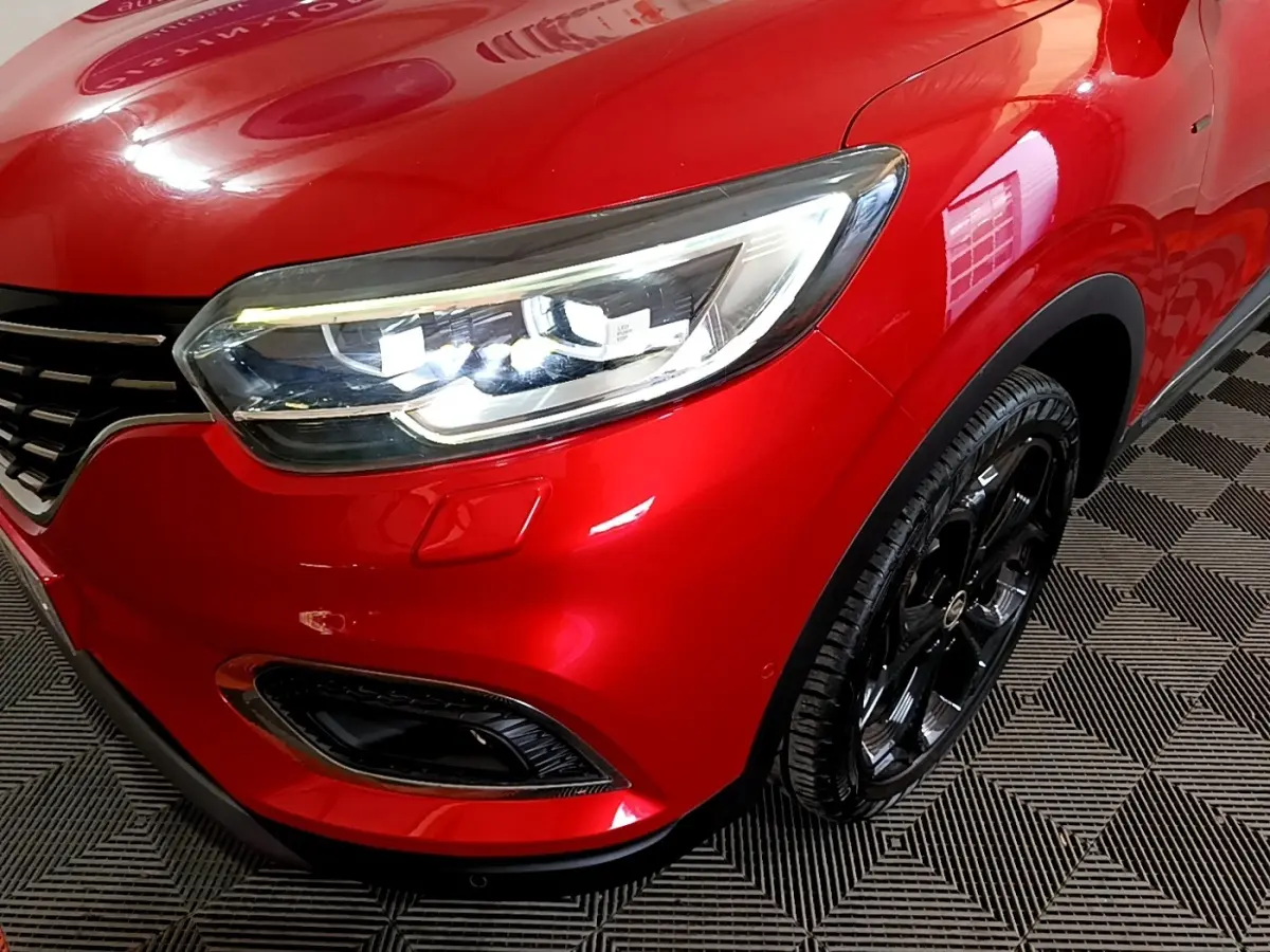 Gros plan sur l'avant droit rouge brillant du Renault Kadjar SL Black Edition avec phare LED et jante noire.
