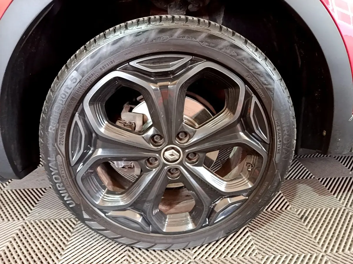 Gros plan sur la roue avant droite du Renault Kadjar rouge, jante alliage noire au design hexagonal.