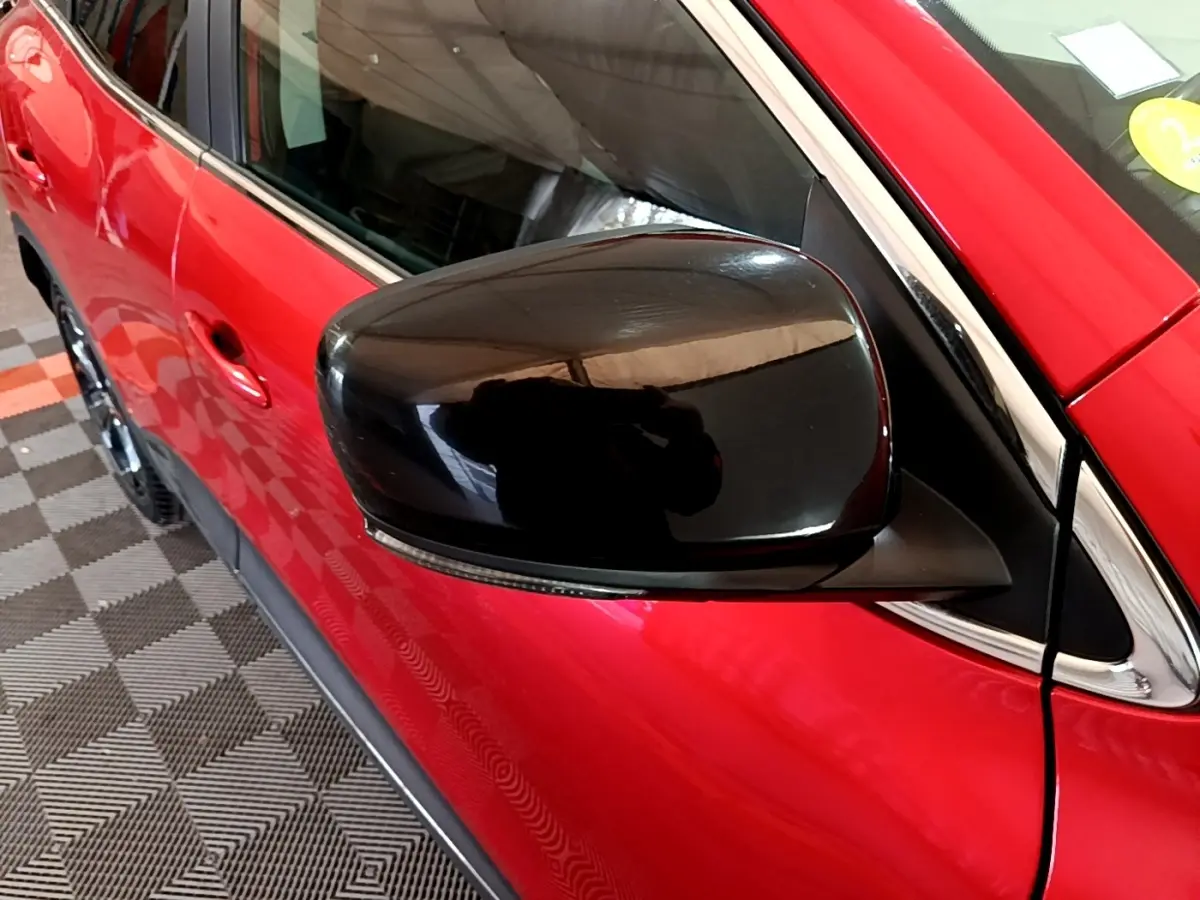 Rétroviseur noir en gros plan côté gauche sur Renault Kadjar SL Black Edition rouge vue partielle côté avant.