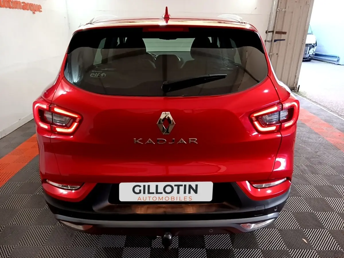 Vue arrière d’un Renault Kadjar rouge avec feux LED et logo central, stationné en intérieur sur sol damier.