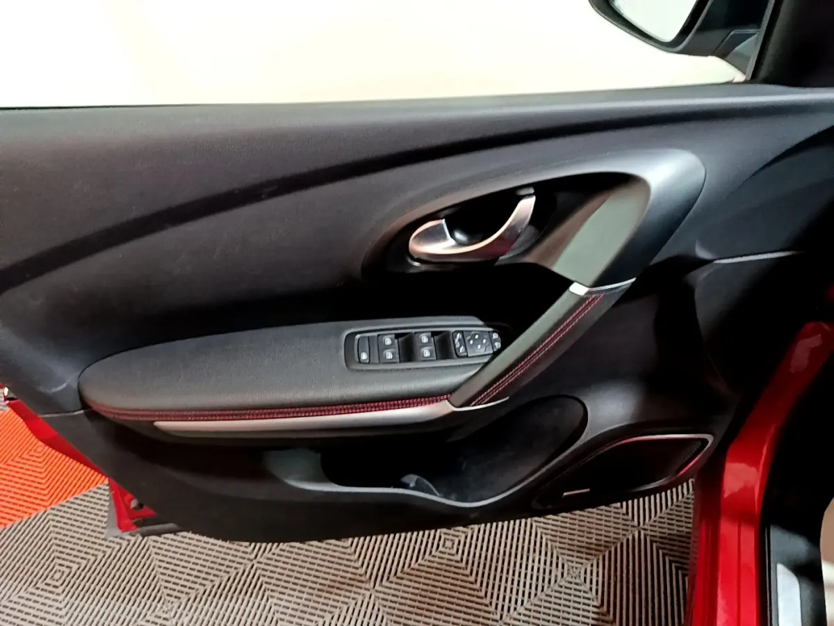 Vue rapprochée de la porte avant gauche rouge du Renault Kadjar SL Black Edition avec commandes de vitres et poignée chrome.