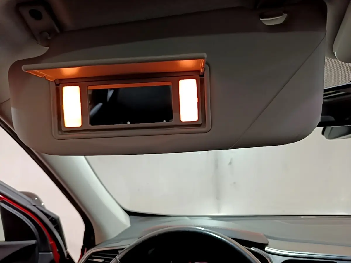 Vue intérieure du pare-soleil avec miroir éclairé du Renault Kadjar rouge, côté conducteur, tableau de bord visible.