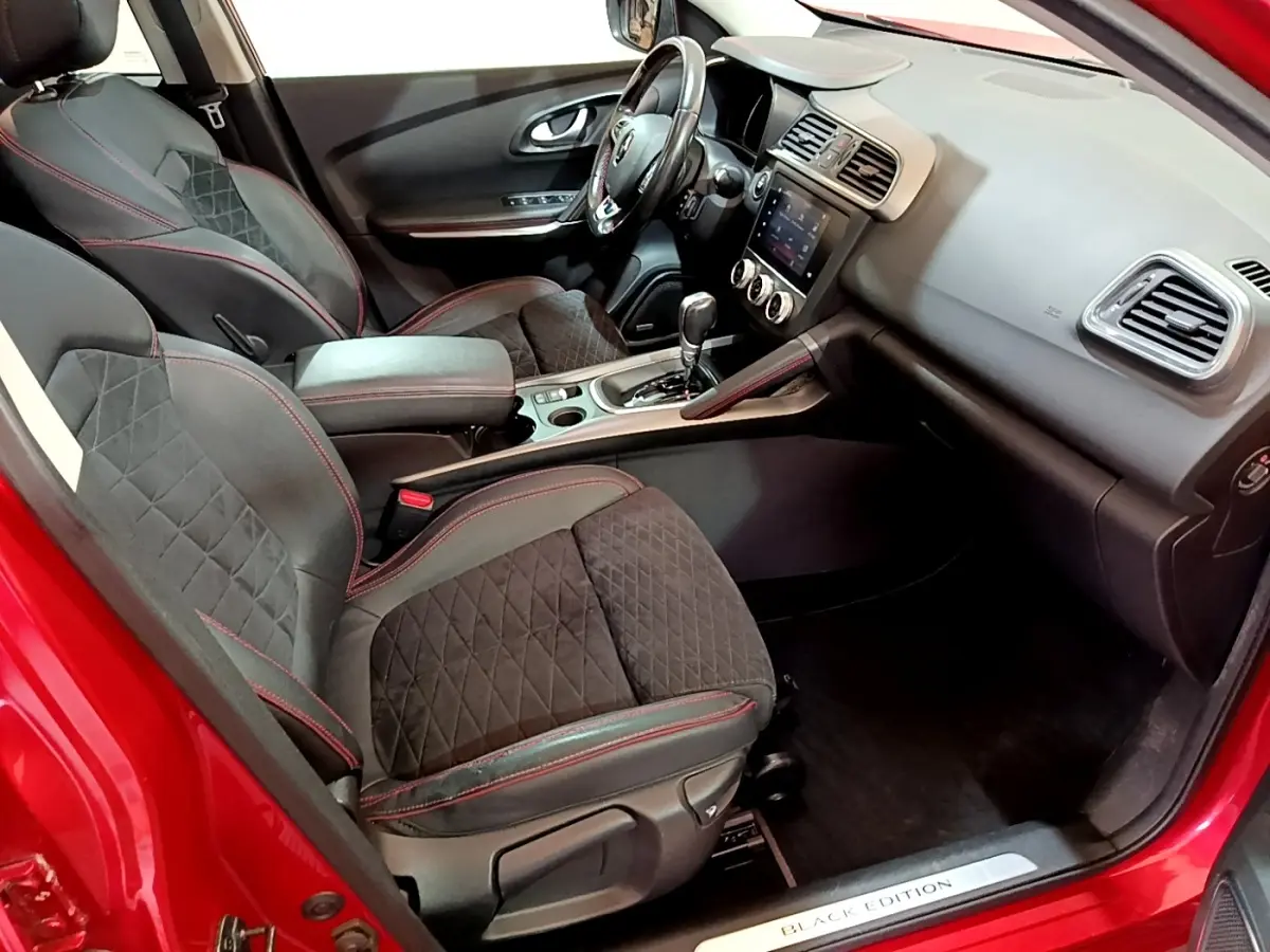 Vue intérieure côté conducteur du Renault Kadjar rouge, sièges noirs avec surpiqûres rouges et console centrale avec écran tactile.