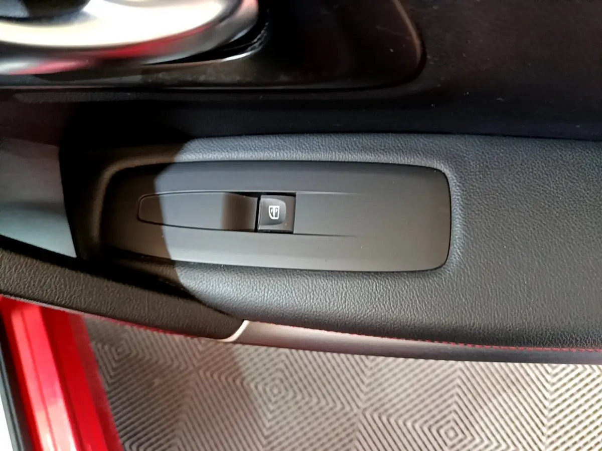 Gros plan sur le bouton de commande de la vitre électrique côté conducteur du Renault Kadjar rouge, intérieur noir.