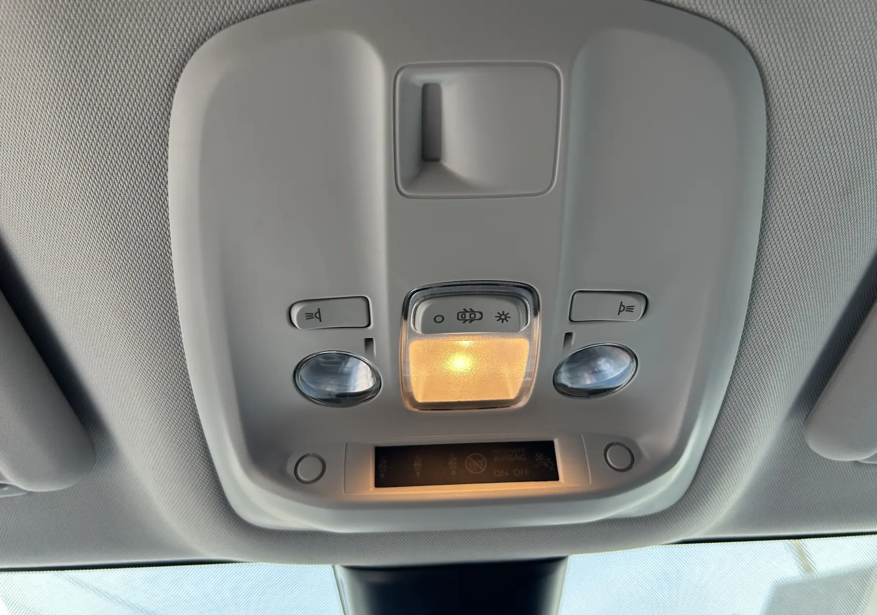 Plafonnier intérieur avec éclairage central allumé et commandes de lumière dans un Opel Vivaro Combi noir, vue de dessous.