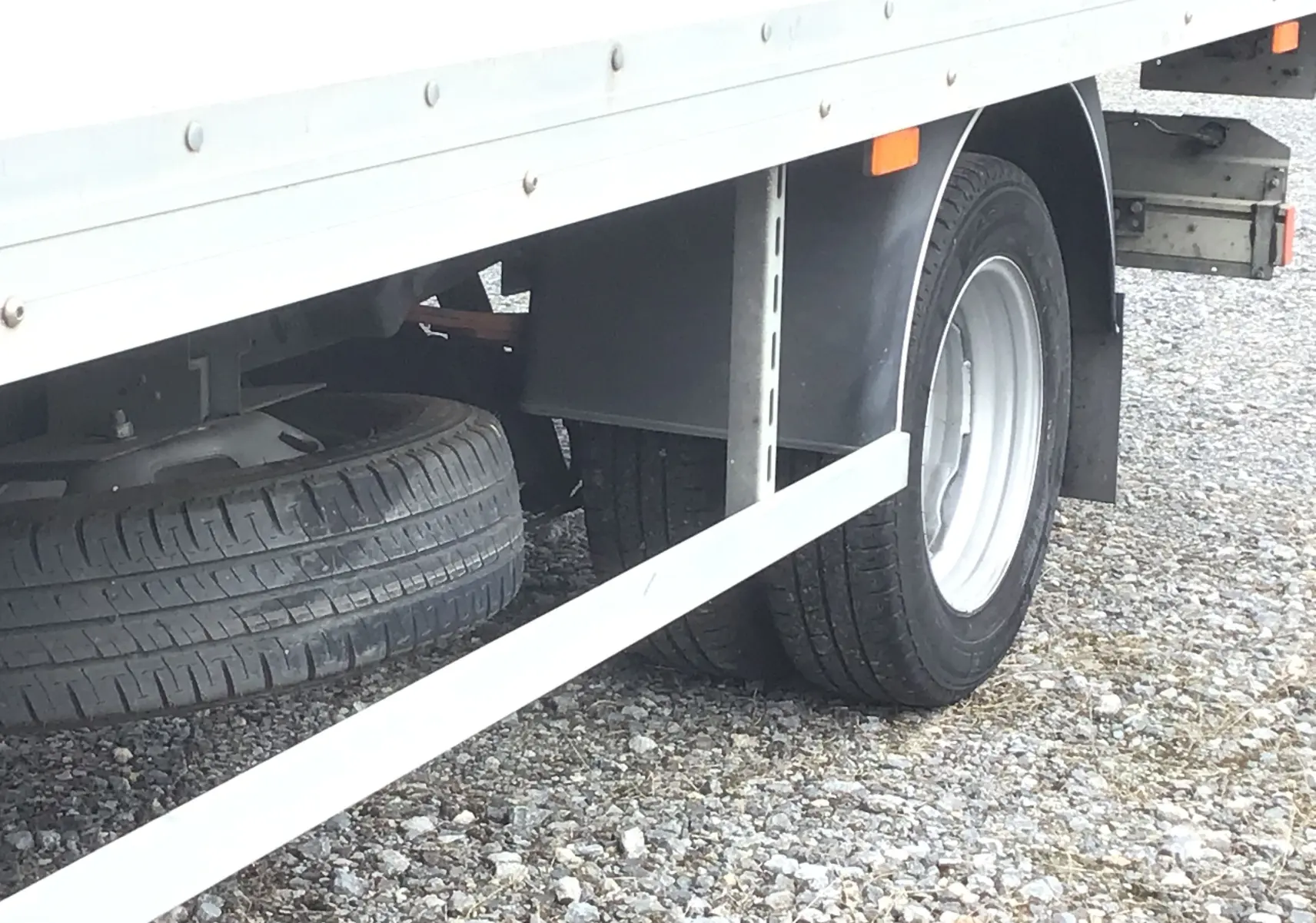Gros plan sur la roue arrière droite du camion blanc Iveco Daily Chassis Cabine 35C16 avec caisse 20m3 et hayon.