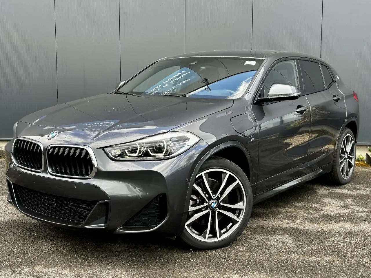 BMW X2 gris minéral en vue 3/4 avant droit avec jantes alliage bicolores et calandre M Sport distinctive.