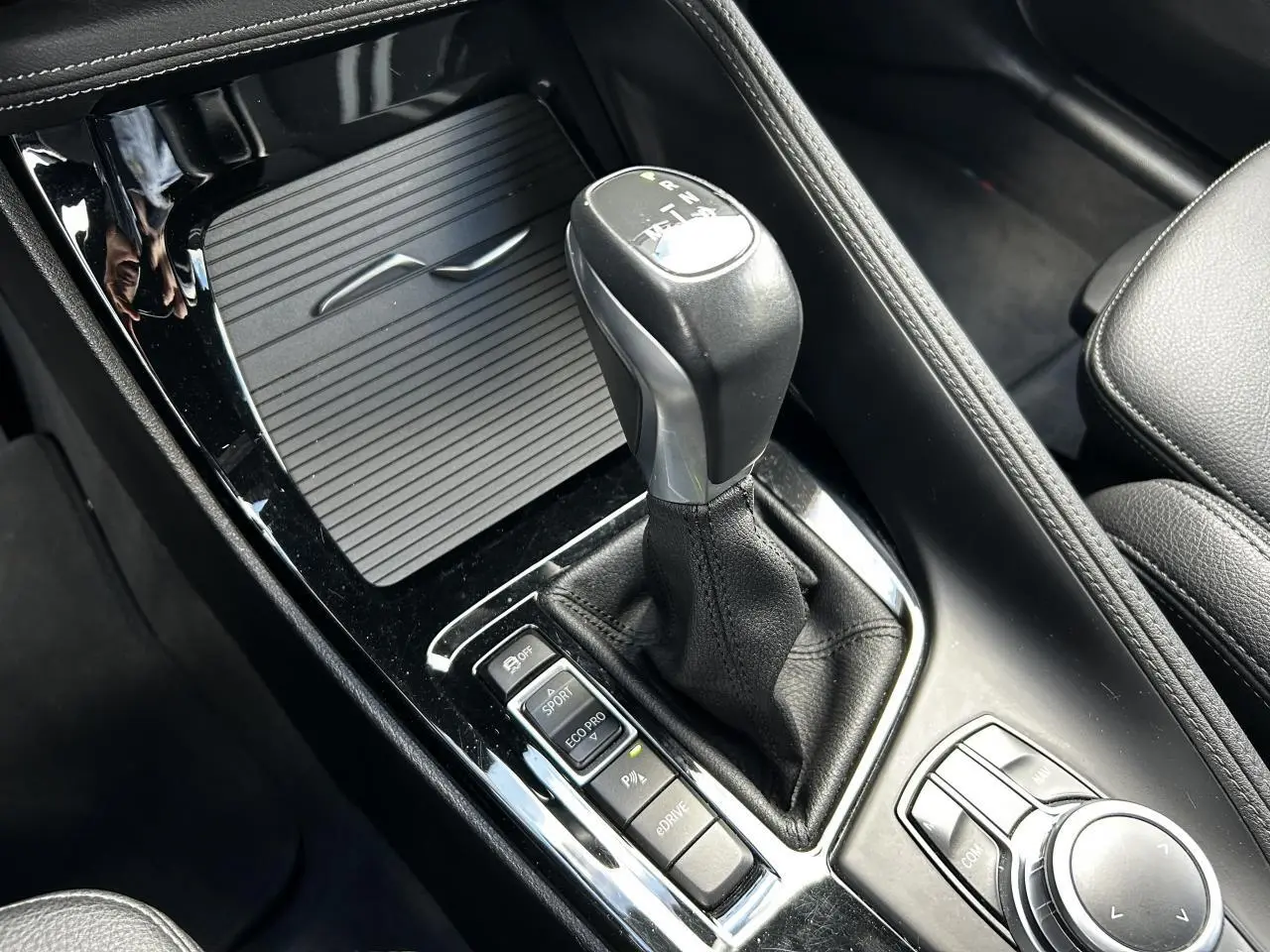 Gros plan sur la console centrale noire du BMW X2 F39, mettant en valeur le levier de vitesses automatique et les boutons de mode de conduite.