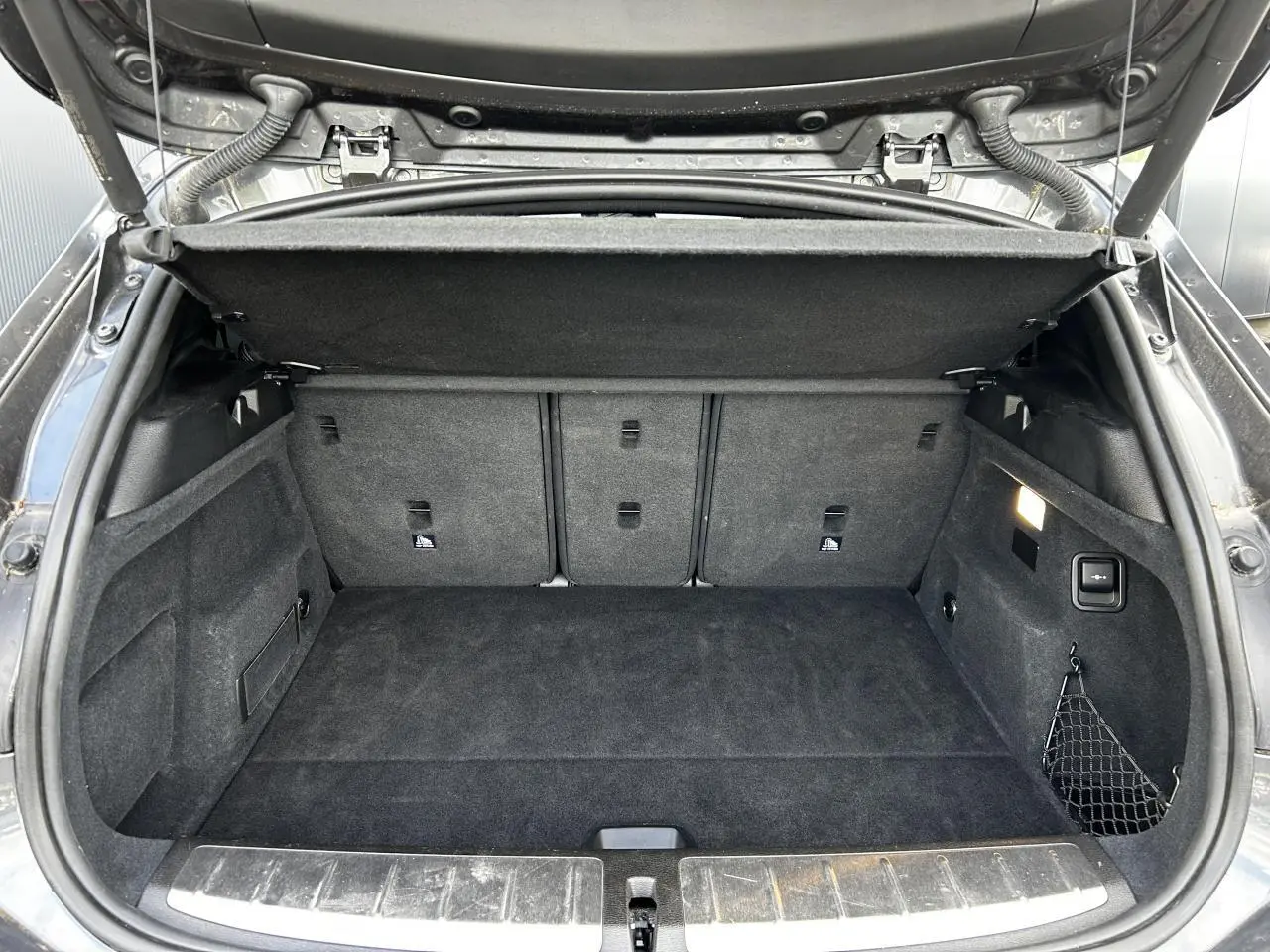 Coffre ouvert d'une BMW X2 F39 gris Mineral, montrant un espace de chargement propre et bien agencé.