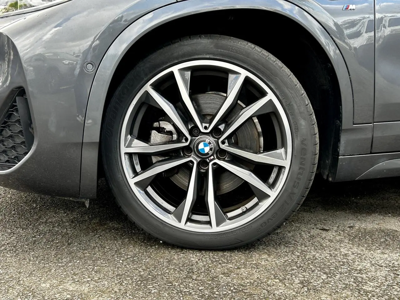 Gros plan sur la jante avant droite bicolore 19 pouces style 919 M d'un BMW X2 gris Mineral avec badge M sur l'aile.