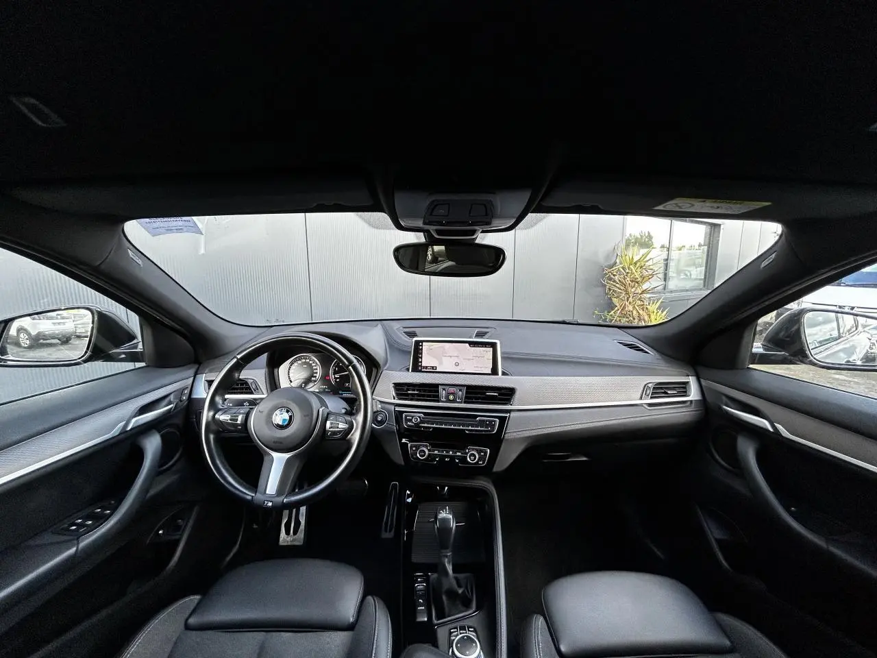 Intérieur noir de BMW X2 F39 2021, vue avant sur tableau de bord avec écran GPS et volant M cuir.