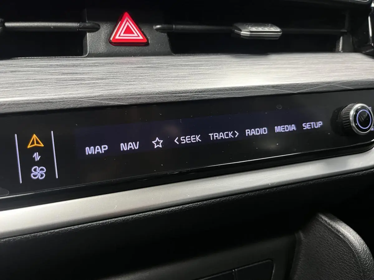 Détail de la console centrale du Kia Sportage 2022, écran tactile avec commandes multimédia et bouton rotatif.