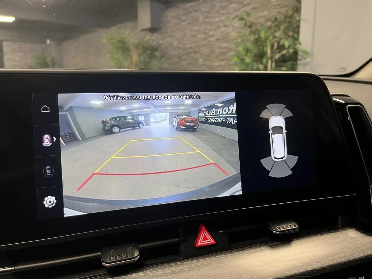 Affichage de la caméra de recul du Kia Sportage blanc, avec lignes de guidage et capteurs de proximité visibles.