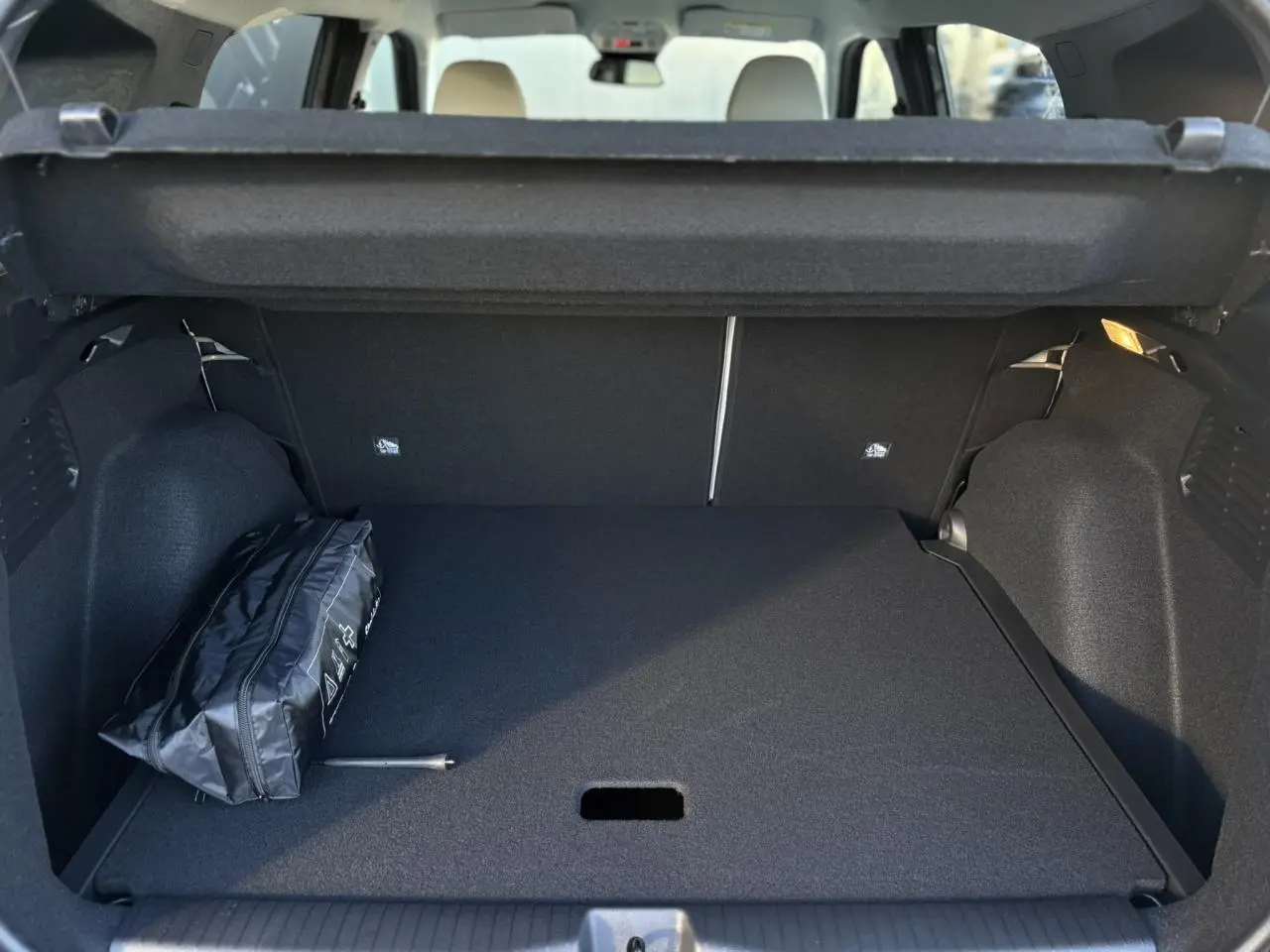 Coffre ouvert d'une Citroën C3 Aircross gris Mercury, montrant un rangement plat avec trousse de secours noire.