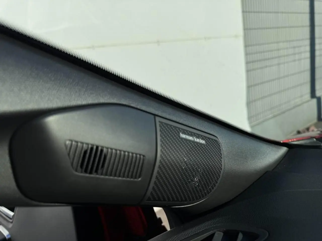 Gros plan sur l'enceinte Harman Kardon côté droit du tableau de bord du Renault Captur II Rouge Flamme toit noir.