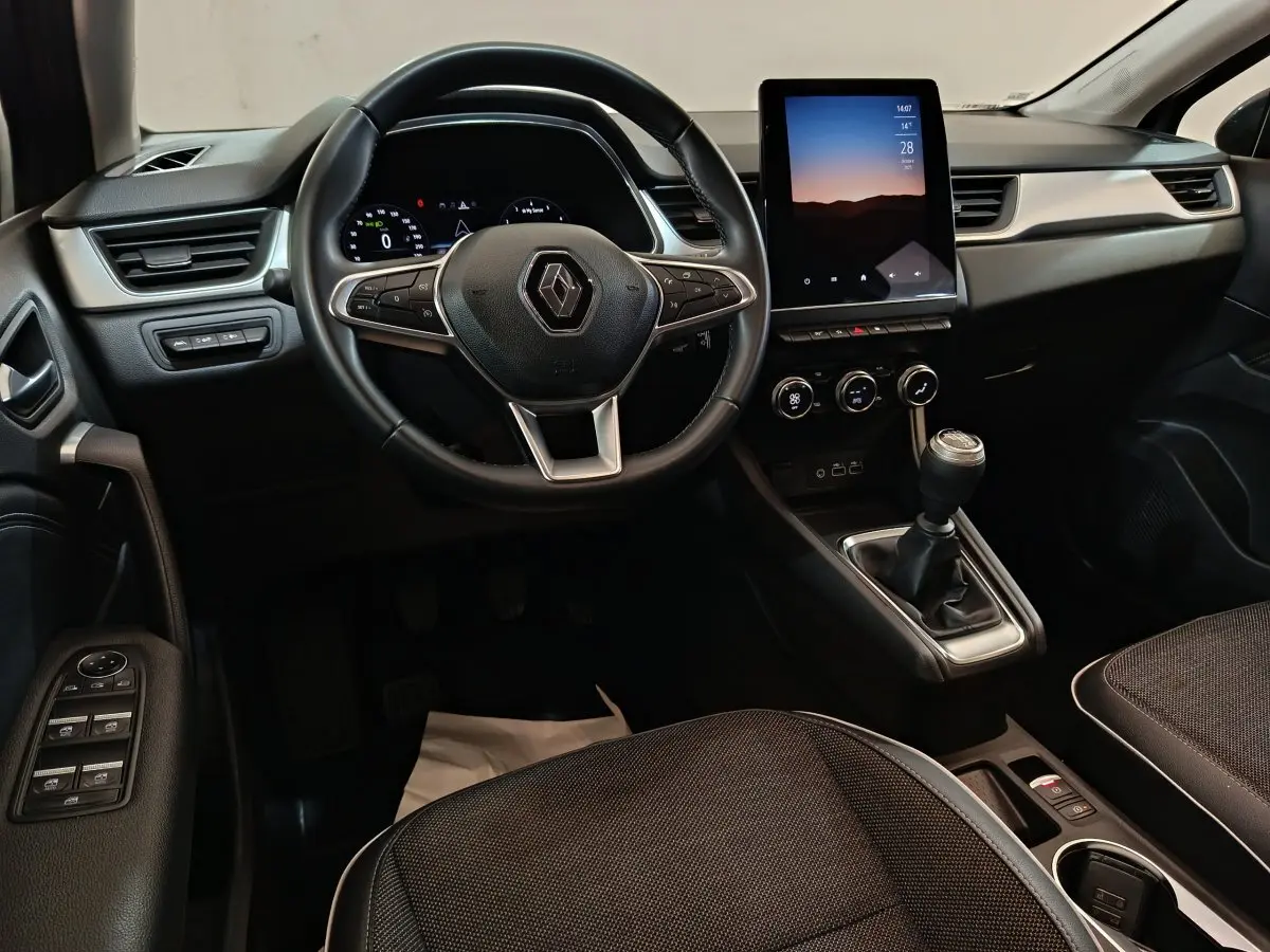Intérieur Renault Captur Techno TCe 90 2024, vue avant centrée sur volant, écran tactile vertical et boîte manuelle noire.
