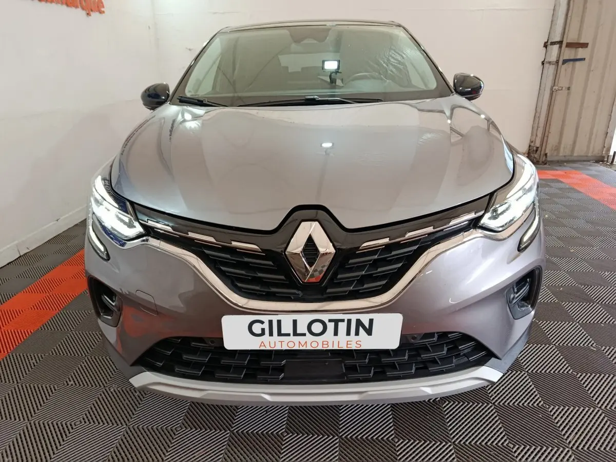 Vue frontale du Renault Captur techno TCe 90 gris foncé avec phares LED allumés et calandre distinctive.