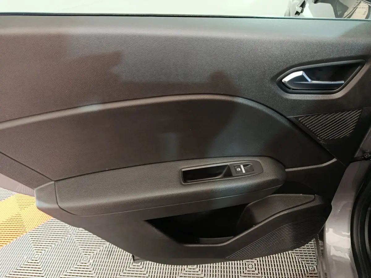 Panneau intérieur côté droit de la porte d'une Renault Captur techno TCe 90 gris foncé avec poignée et commandes de fenêtre.