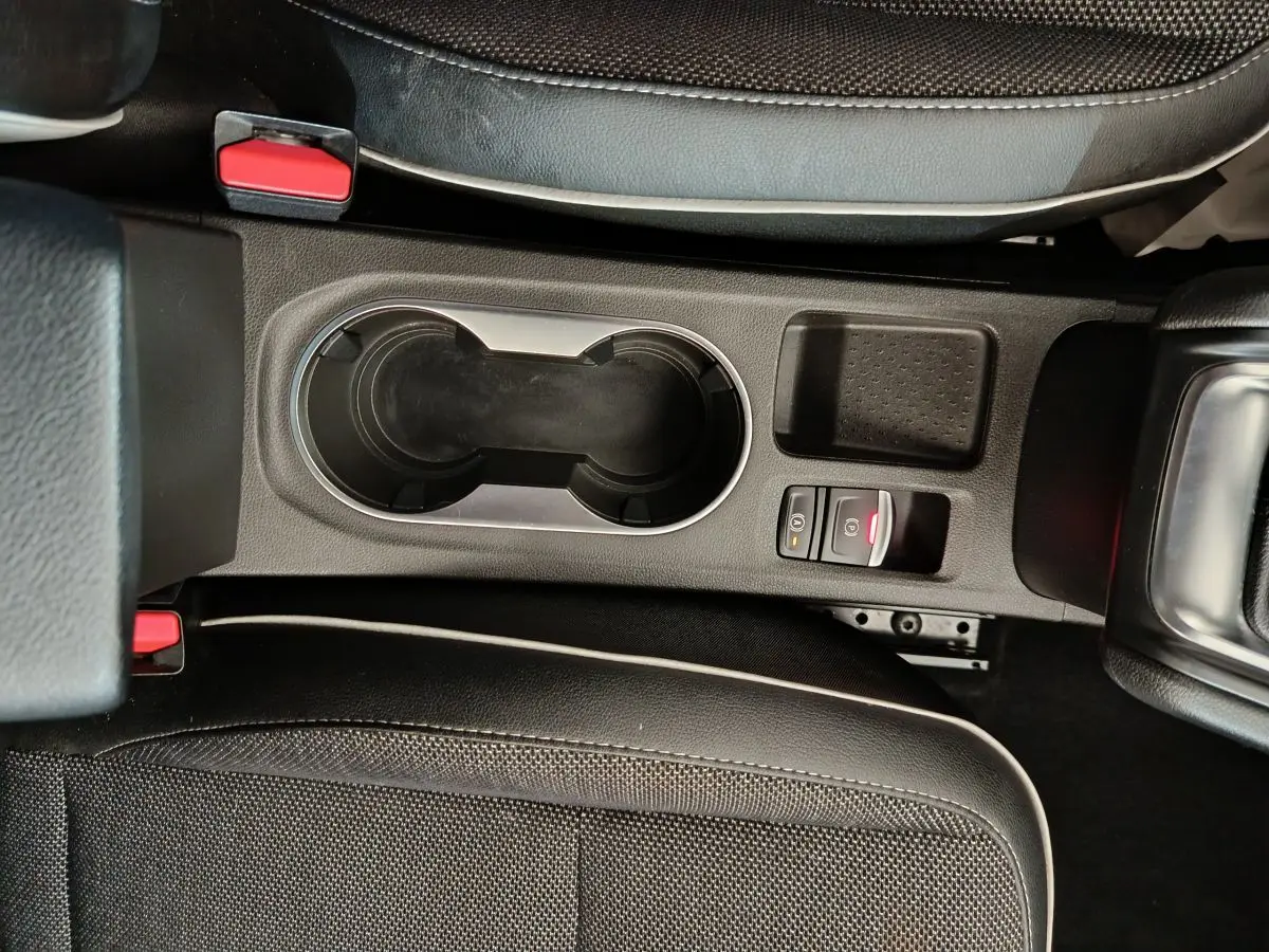 Gros plan sur la console centrale noire du Renault Captur gris foncé 2024 avec frein à main électrique et porte-gobelets.