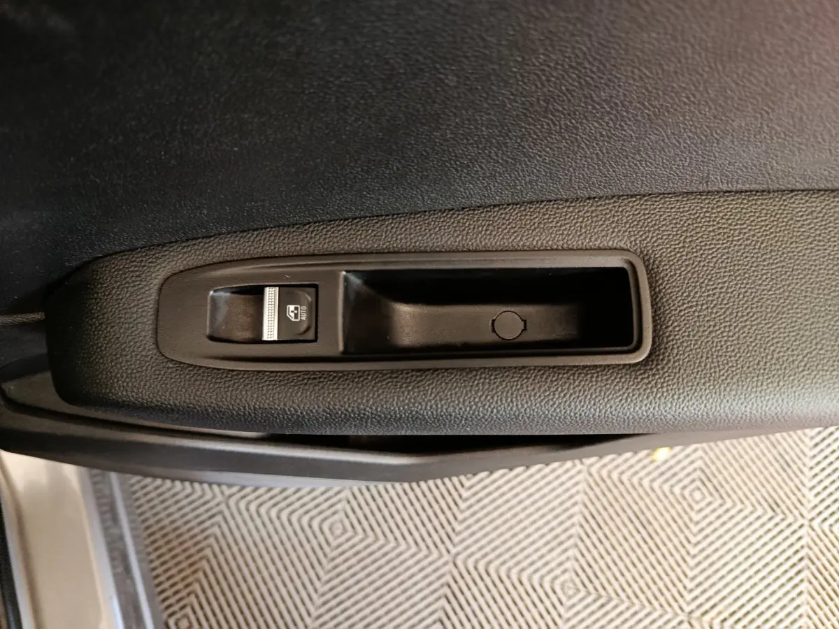 Gros plan sur la commande de lève-vitre côté gauche de la porte intérieure du Renault Captur gris foncé 2024.