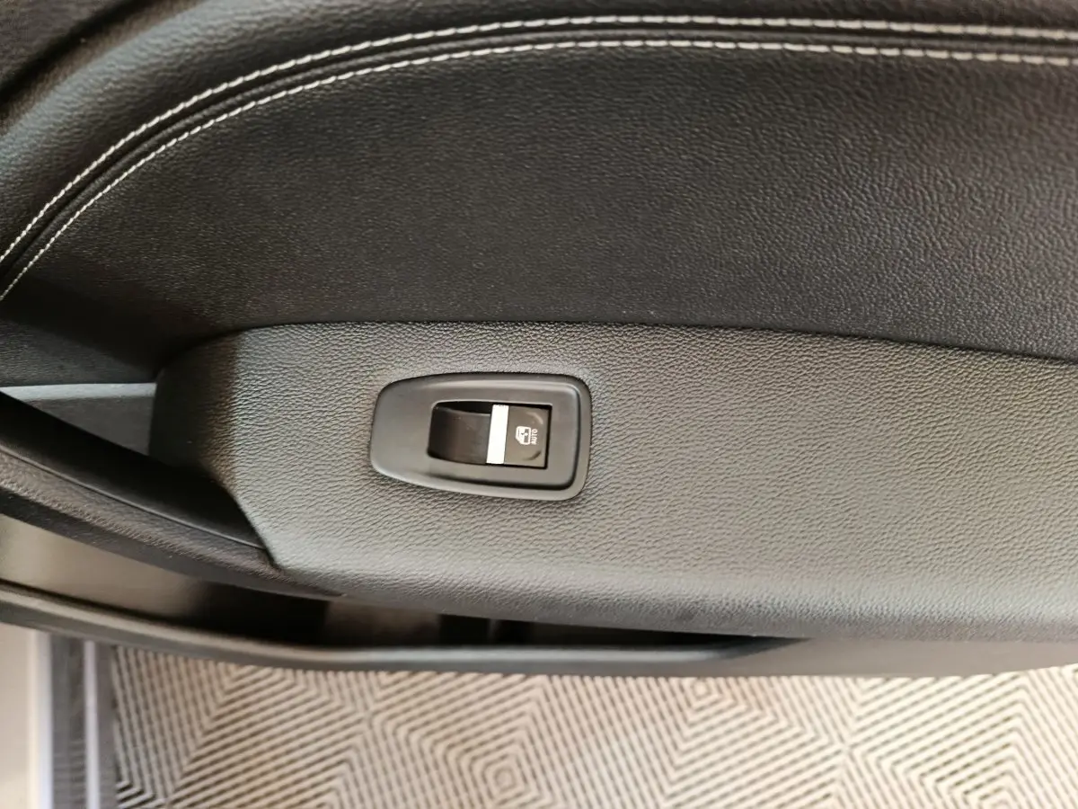 Gros plan sur l'interrupteur de verrouillage des vitres sur la porte intérieure en cuir noir du Renault Captur gris foncé 2024.