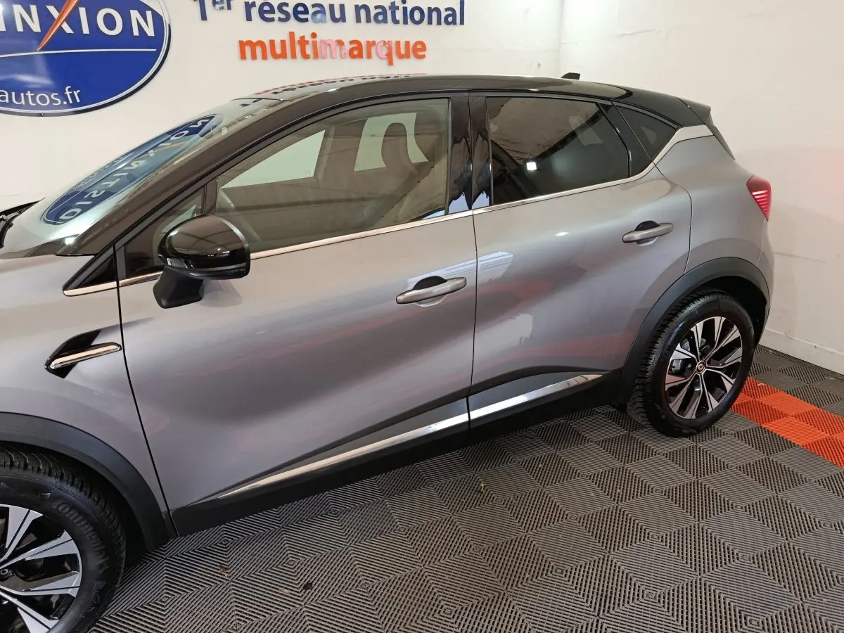 Profil côté gauche d'un Renault Captur techno TCe 90 gris foncé 2024 avec jantes noires et toit noir brillant.