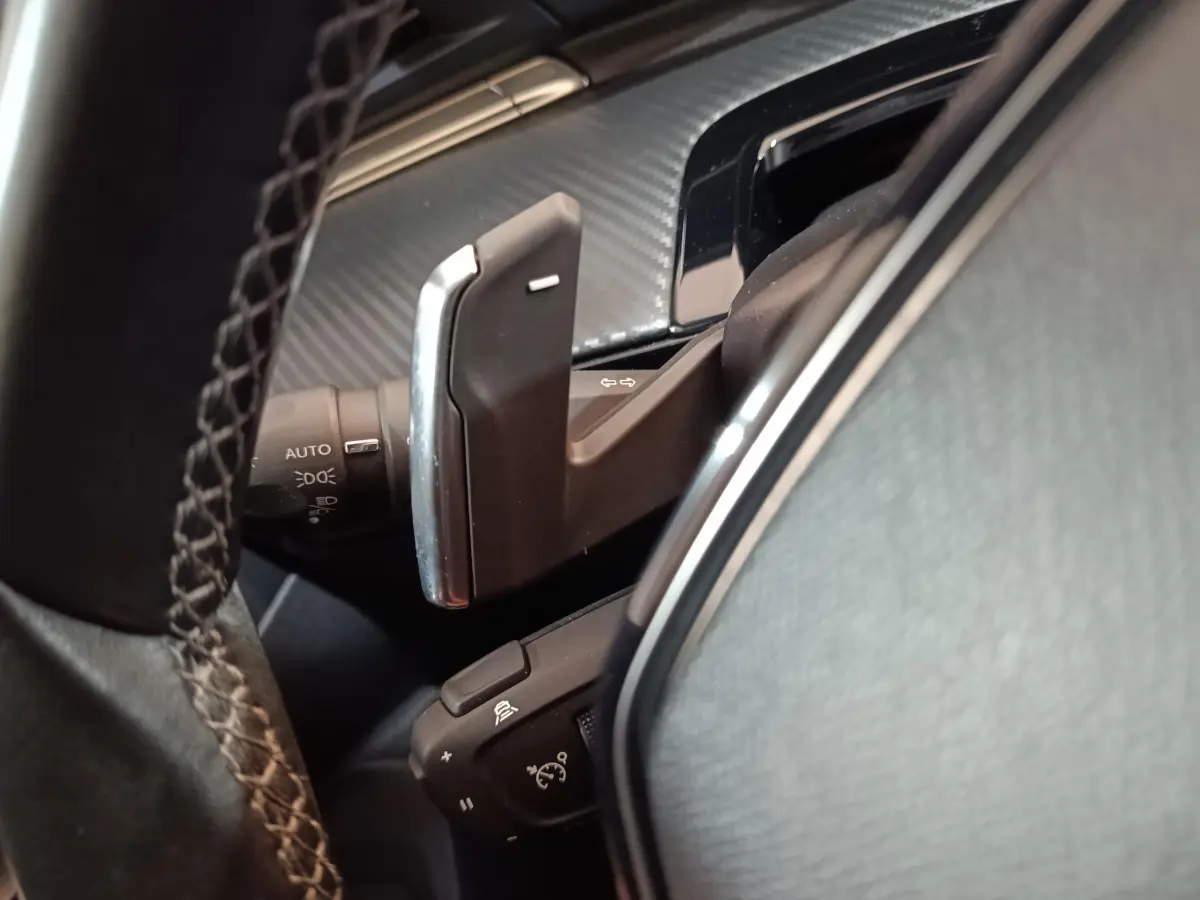Gros plan sur la commande au volant et levier de clignotant dans l’habitacle noir du Peugeot 508 gris clair.