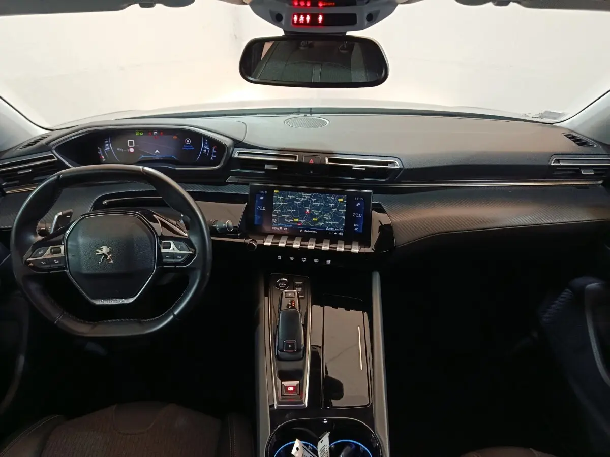 Vue intérieure frontale du tableau de bord noir et volant cuir de la Peugeot 508 gris clair avec écran tactile central allumé.