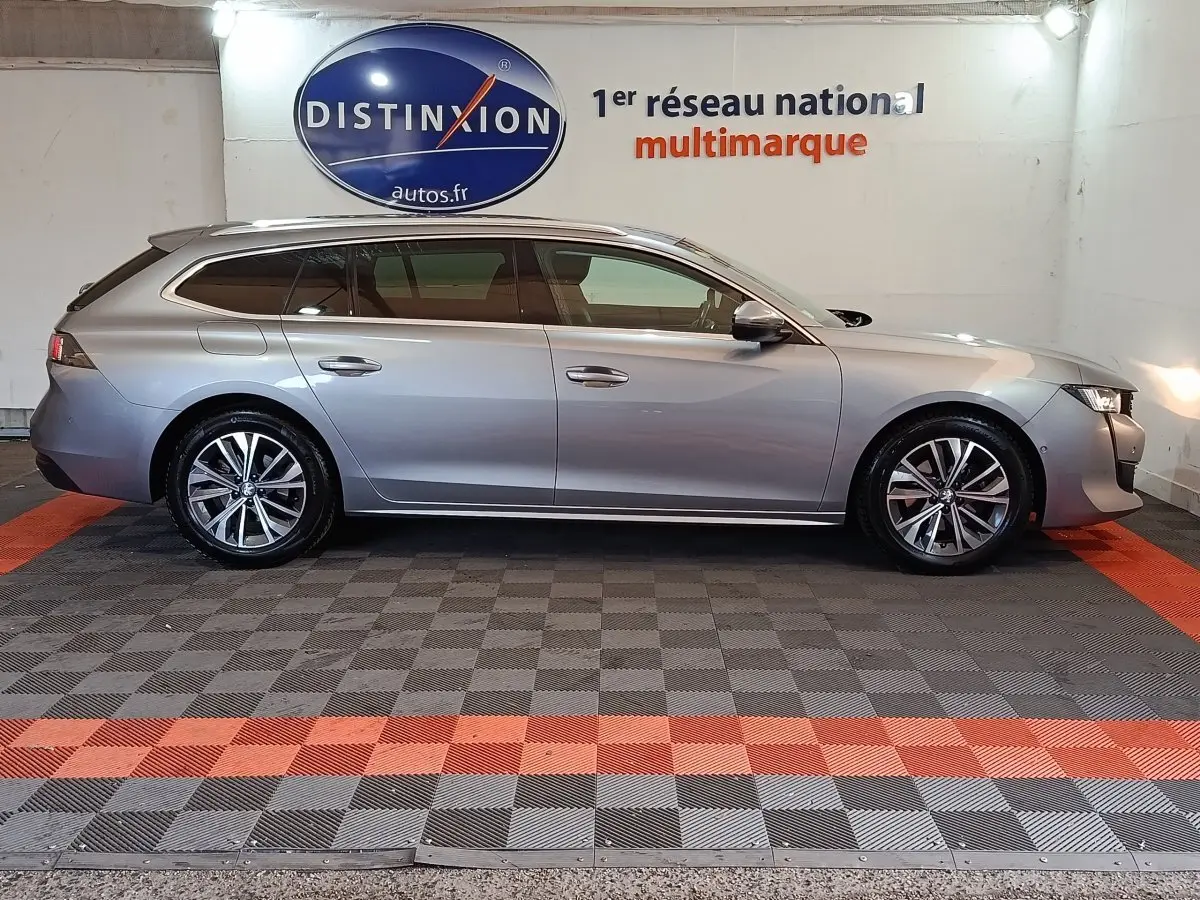 Peugeot 508 BlueHDi gris clair vue de profil côté gauche, break élégant avec jantes alliage et vitres teintées.