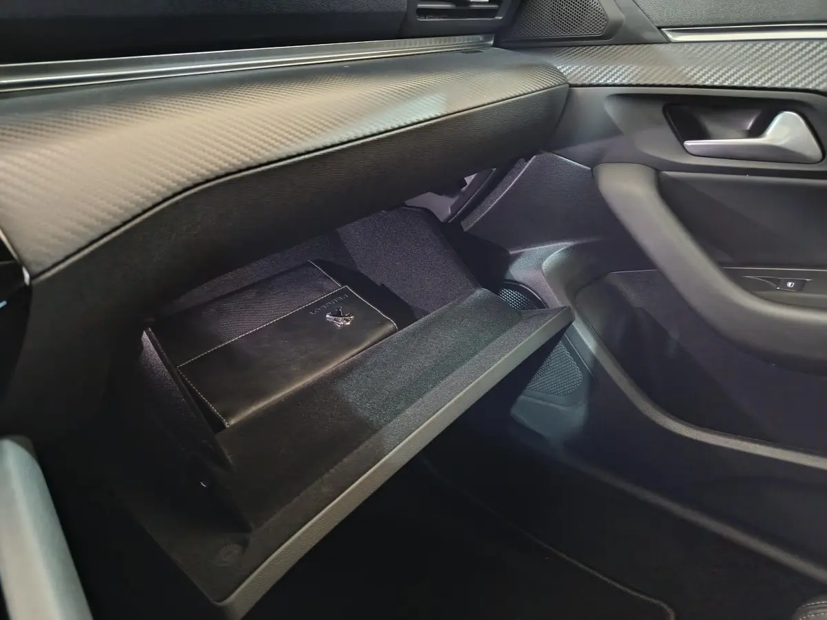 Vue intérieure côté passager de la Peugeot 508 gris clair, boîte à gants ouverte avec manuel Peugeot visible.