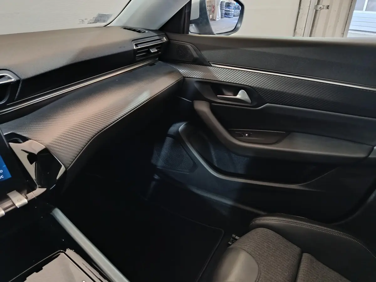 Vue intérieure côté passager de la Peugeot 508 2020 gris clair, tableau de bord texturé et garnitures noires.