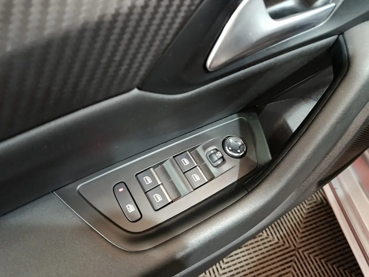 Gros plan sur les commandes de lève-vitres et rétroviseurs côté conducteur de la Peugeot 508 gris clair.