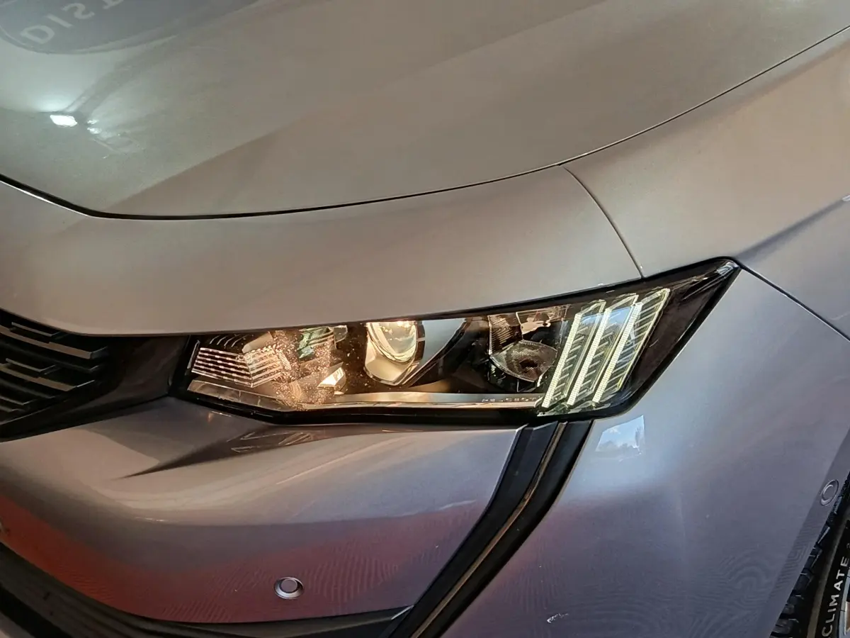 Gros plan sur le phare avant droit d'une Peugeot 508 gris clair, mettant en valeur les feux LED distinctifs.