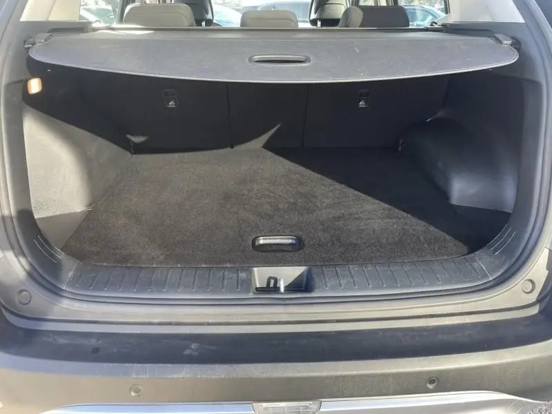 Coffre ouvert du KIA SPORTAGE gris Eclipse Metal, vue arrière montrant un espace de chargement propre et spacieux.