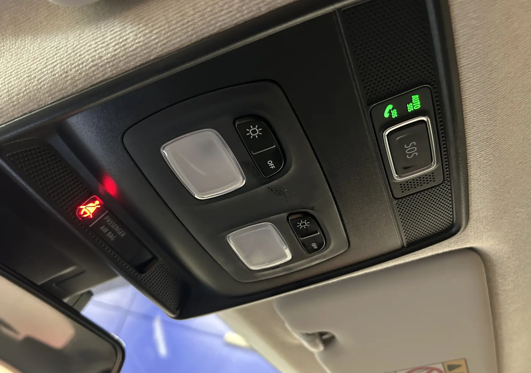 Vue intérieure en gros plan du plafonnier noir avec commandes d’éclairage et bouton SOS allumé dans une Renault Clio V blanche.