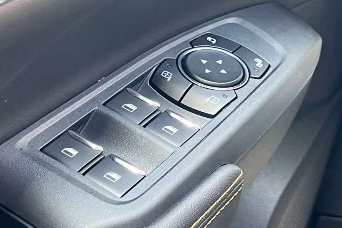 Gros plan sur les commandes des vitres électriques et rétroviseurs du côté conducteur du Ford Ranger Wildtrak Plus noir agate.