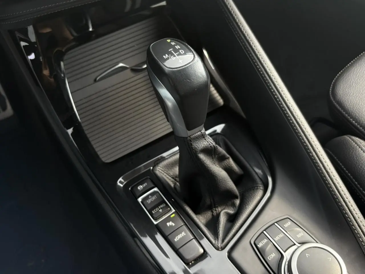 Gros plan sur la console centrale du BMW X2 or Galvanic, avec levier de vitesses automatique et commandes de conduite.