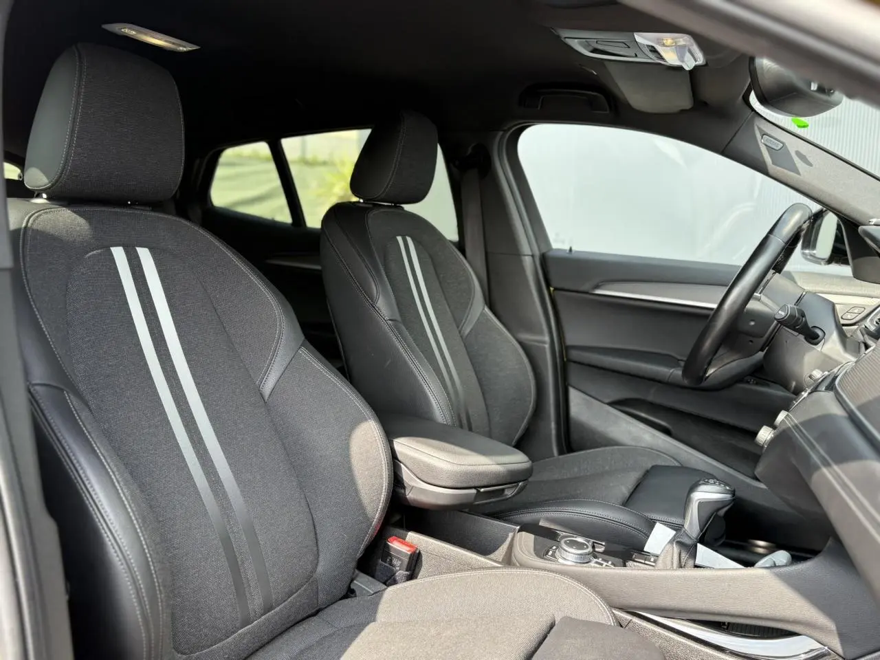Intérieur de la BMW X2 F39 2021 vu côté droit, sièges sport noirs avec bandes grises et accoudoir central.